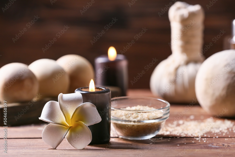 木桌上燃烧的蜡烛、一碗海盐和热带花卉