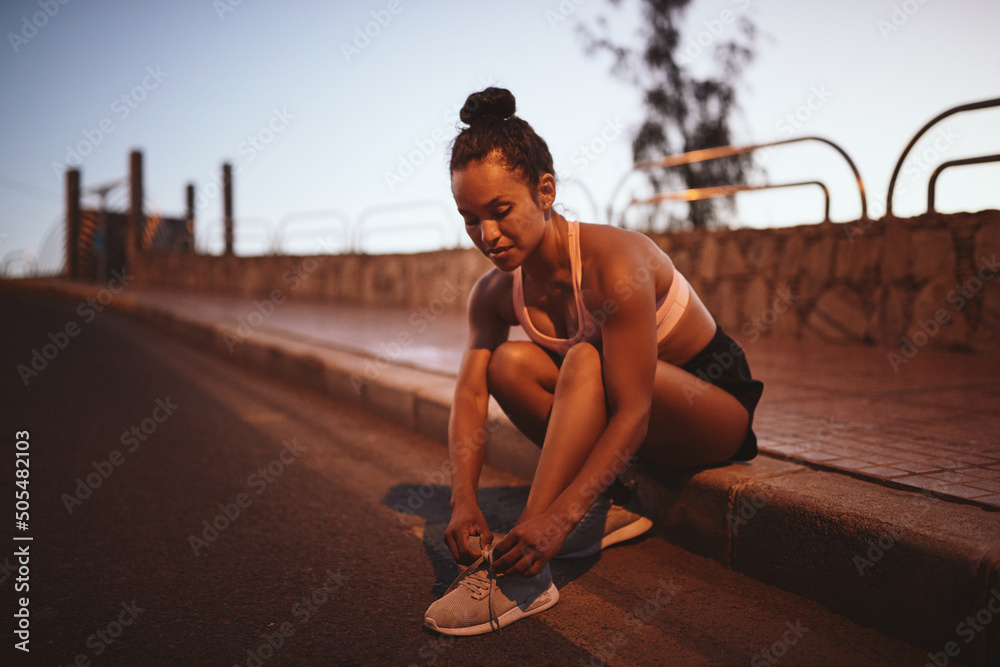 健康的年轻女子在跑步前系好跑鞋