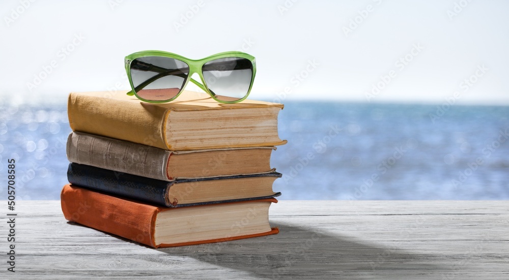 Stack of colored books and sunglasses on the desk