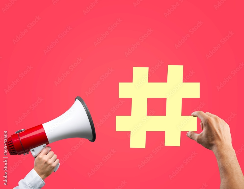 Hands holding megaphone with yellow hashtag sign. Concept social network monitoring, media measureme