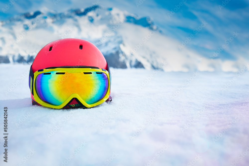 带滑雪面罩的粉色头盔在山脉上空的雪地里