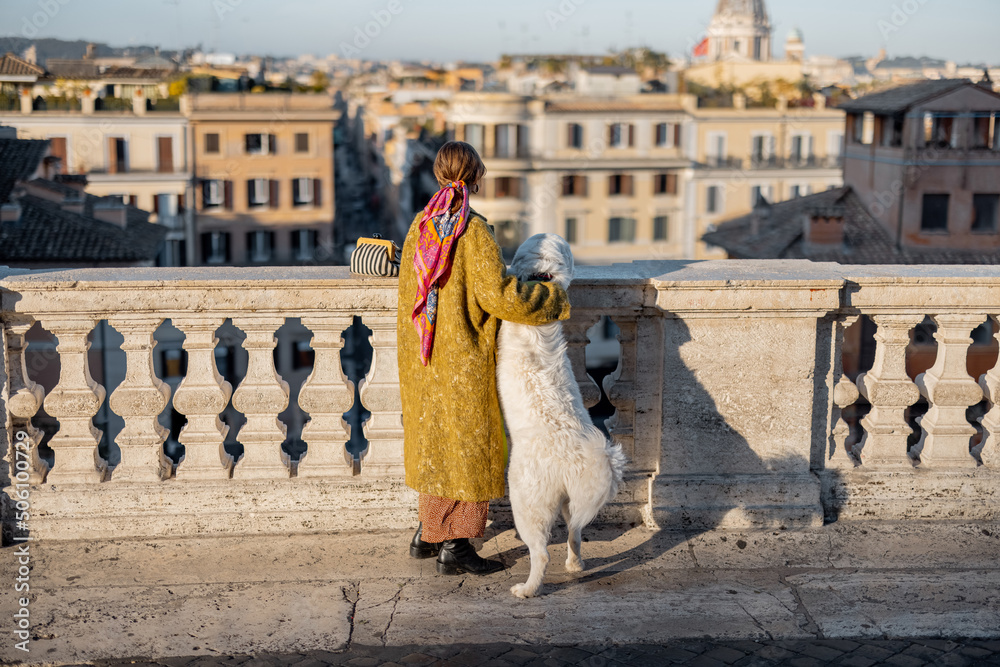 一个女人享受着古老罗马城美丽的城市景观，她和她的狗站在西班牙语的顶端