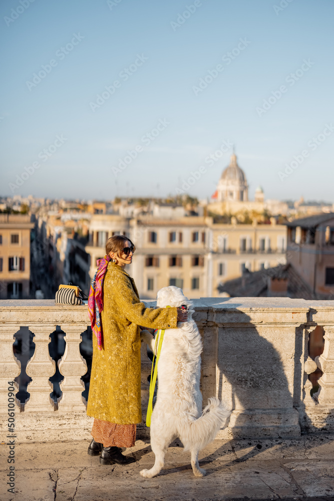 Woman enjoys beautiful cityscape of old Rome city, standing back with her dog on the top of Spanish 