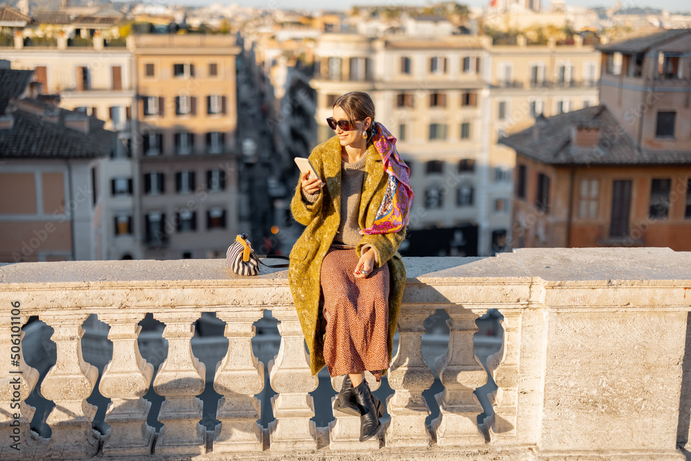 一个女人坐在著名的西班牙台阶上，欣赏着罗马美丽的早晨城市景观。老