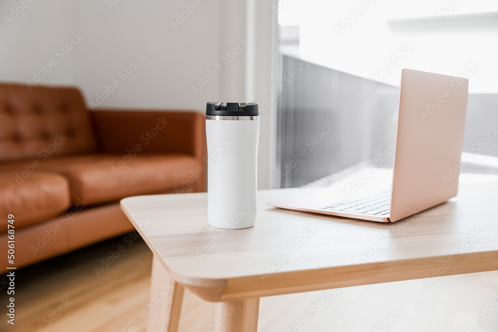 客厅咖啡桌上的笔记本电脑和保温瓶