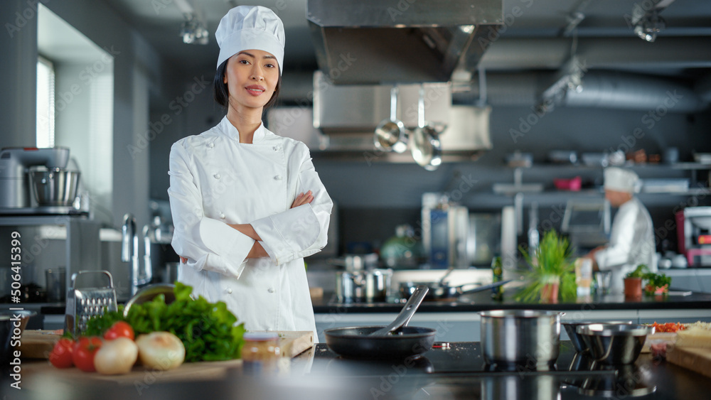 现代厨房餐厅：亚洲女厨师的肖像，双臂交叉，看着镜头的微笑