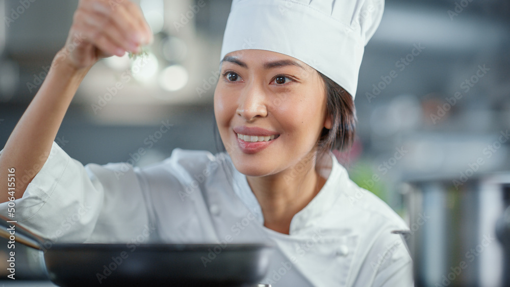 Restaurant Kitchen: Portrait of Asian Female Chef Fries Uses Pan, Seasons Dish with Herbs and Spices