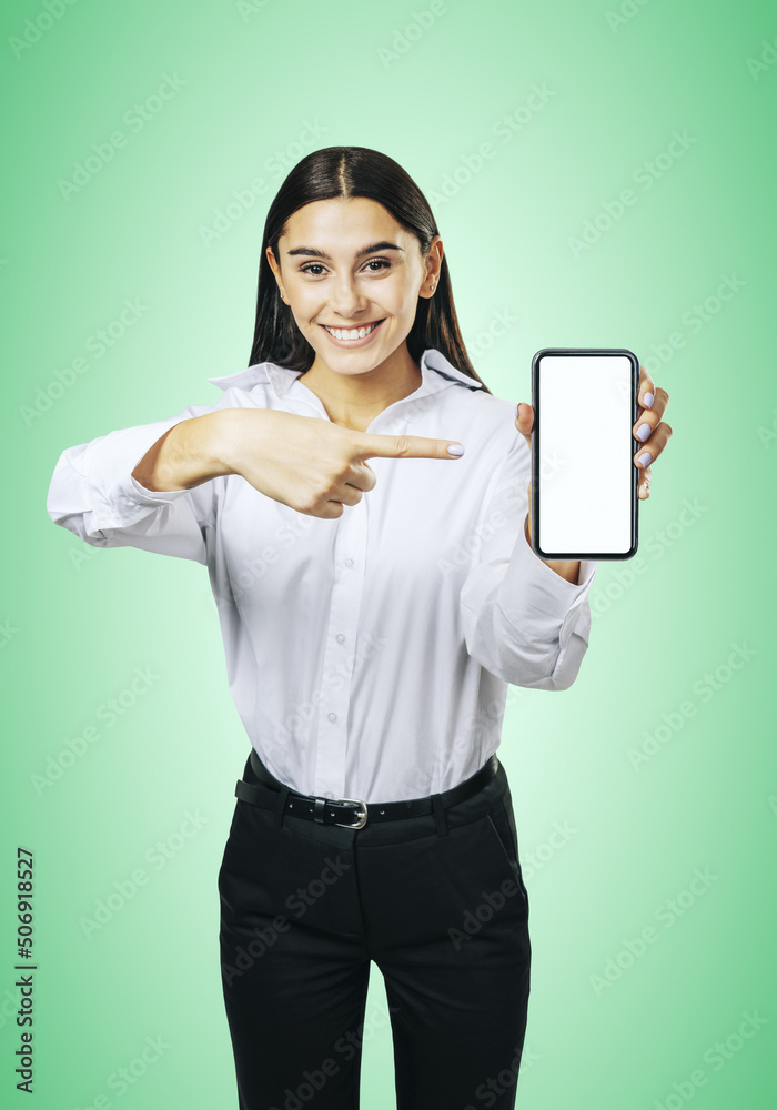 穿着白衬衫的快乐女孩用白色空白展示现代智能手机的移动应用概念