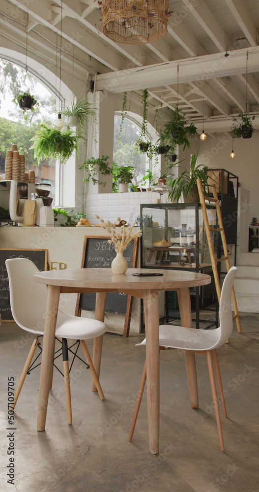 咖啡机上方有桌子和椅子的空咖啡馆的垂直图像