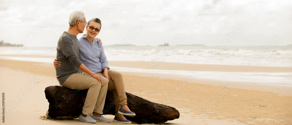 Asian Senior couple  enjoy life on the beach  at sunrise