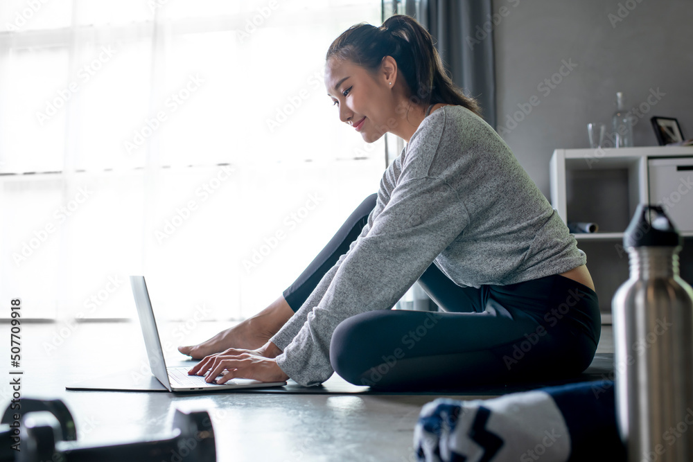 运动型年轻亚洲女性在家锻炼，在网上看健身视频或在线健身
