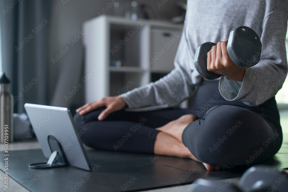 运动型年轻亚洲女性在家锻炼，在网上看健身视频或在线健身