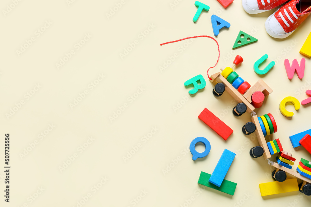 Toy train with building blocks, letters and booties on beige background