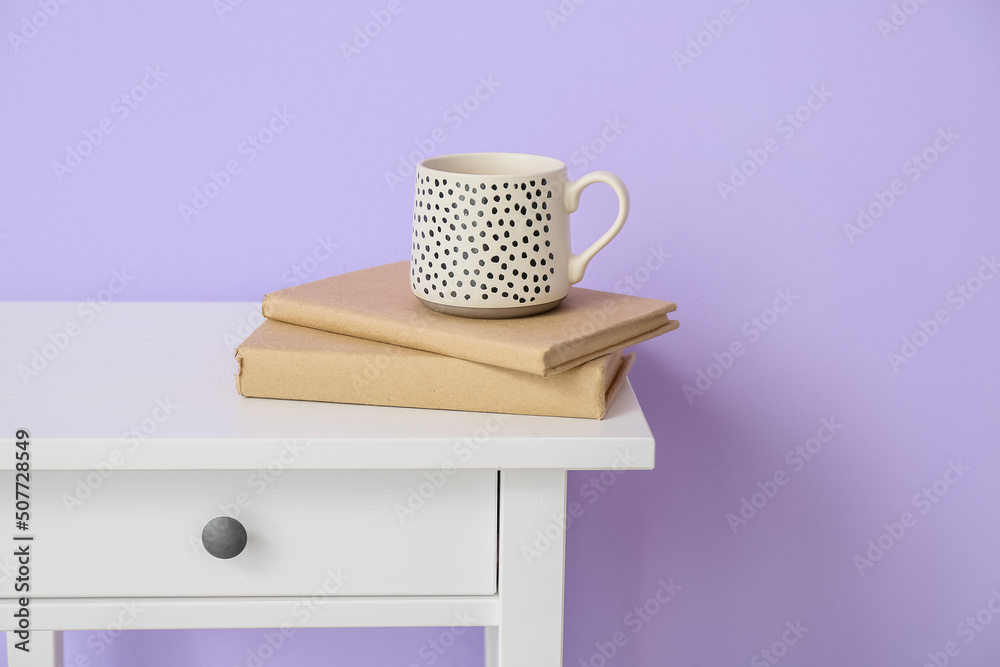 紫色墙壁附近的桌子，有书和杯子