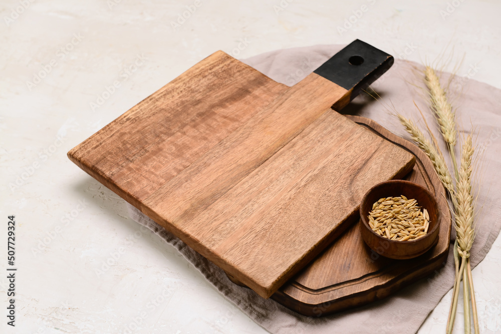 Wooden cutting boards and bowl of wheat grains on light background