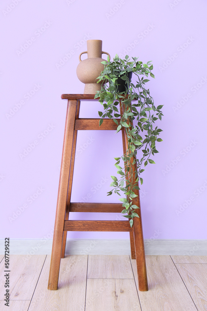 紫丁香墙附近的木凳上有室内植物的花瓶