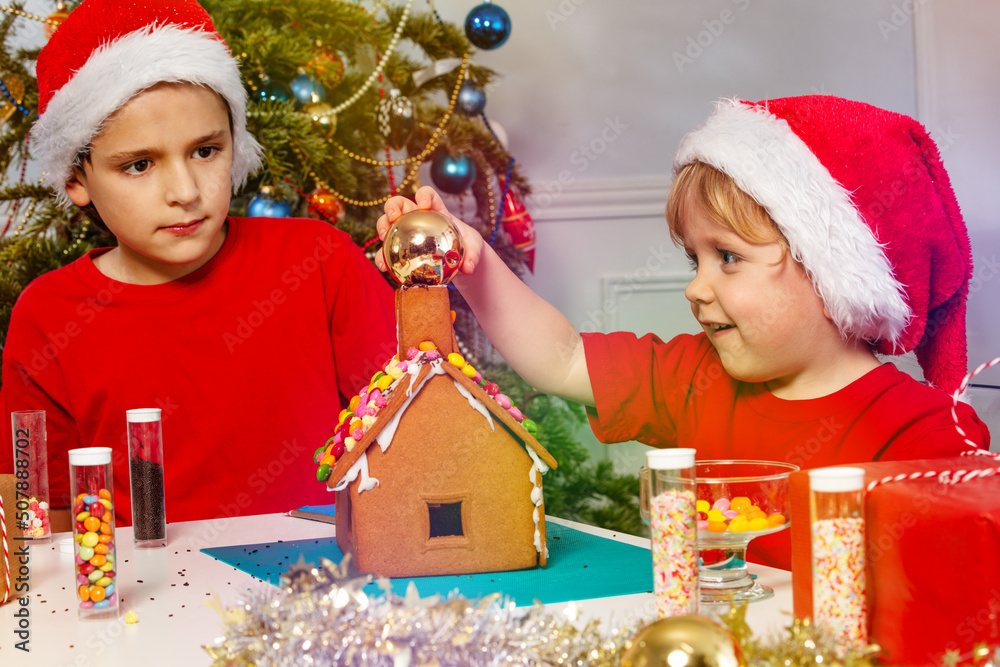Two boys in Santa hat play using Christmas decorations