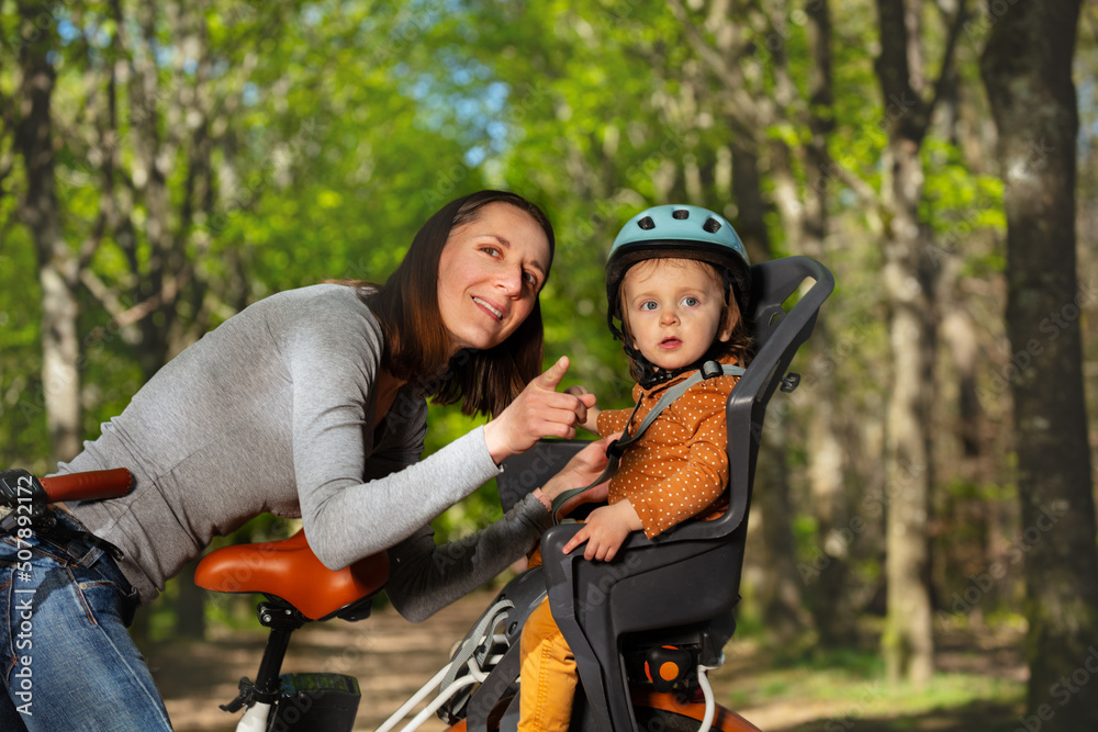 女人玩坐在电动自行车里的孩子指指点点