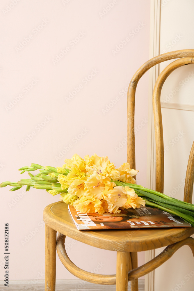 Bouquet of beautiful gladiolus flowers and magazine on chair in room, closeup