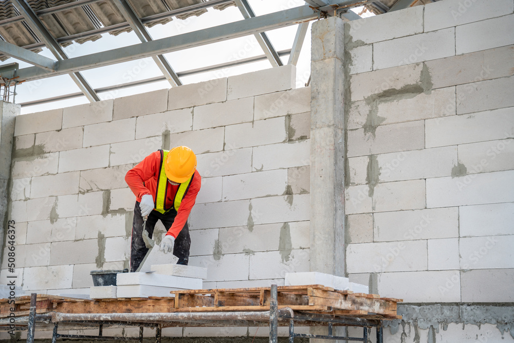 一名建筑工人正在施工现场使用粘合砂浆进行轻质砌砖。