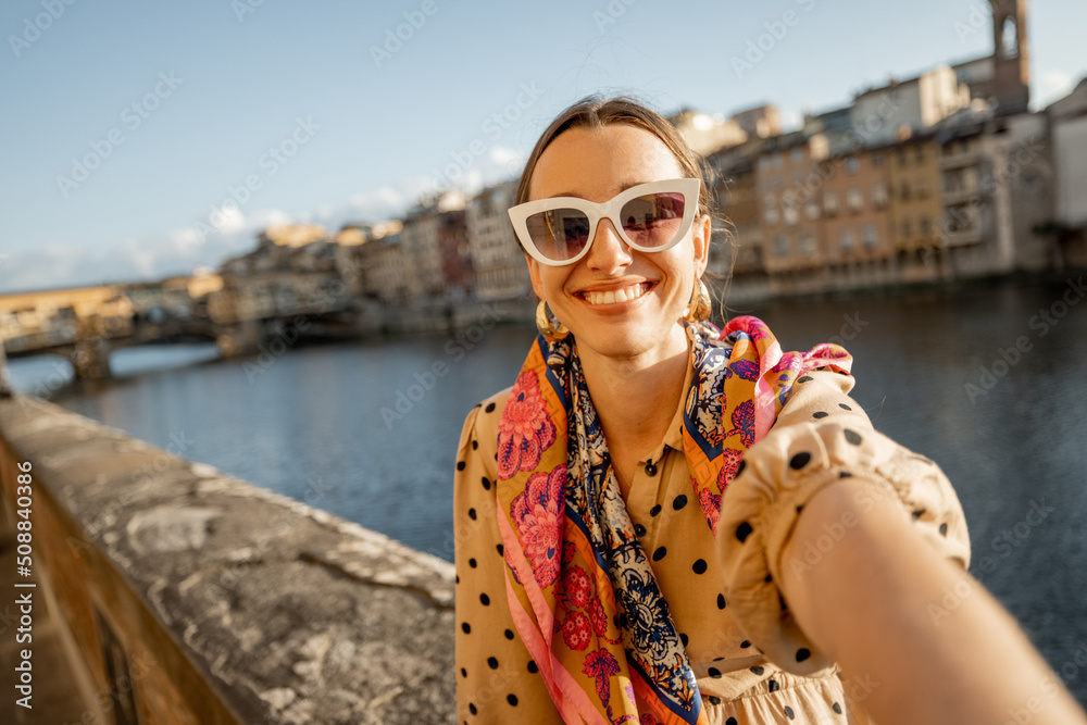 Young woman taking selfie photo on background of famous Old bridge in Florence. Female traveler visi