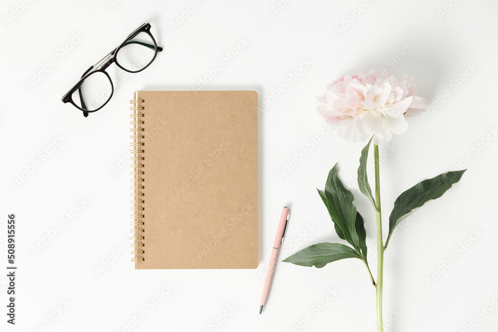 极简风格的平躺，牡丹花和空白笔记本。规划师模型