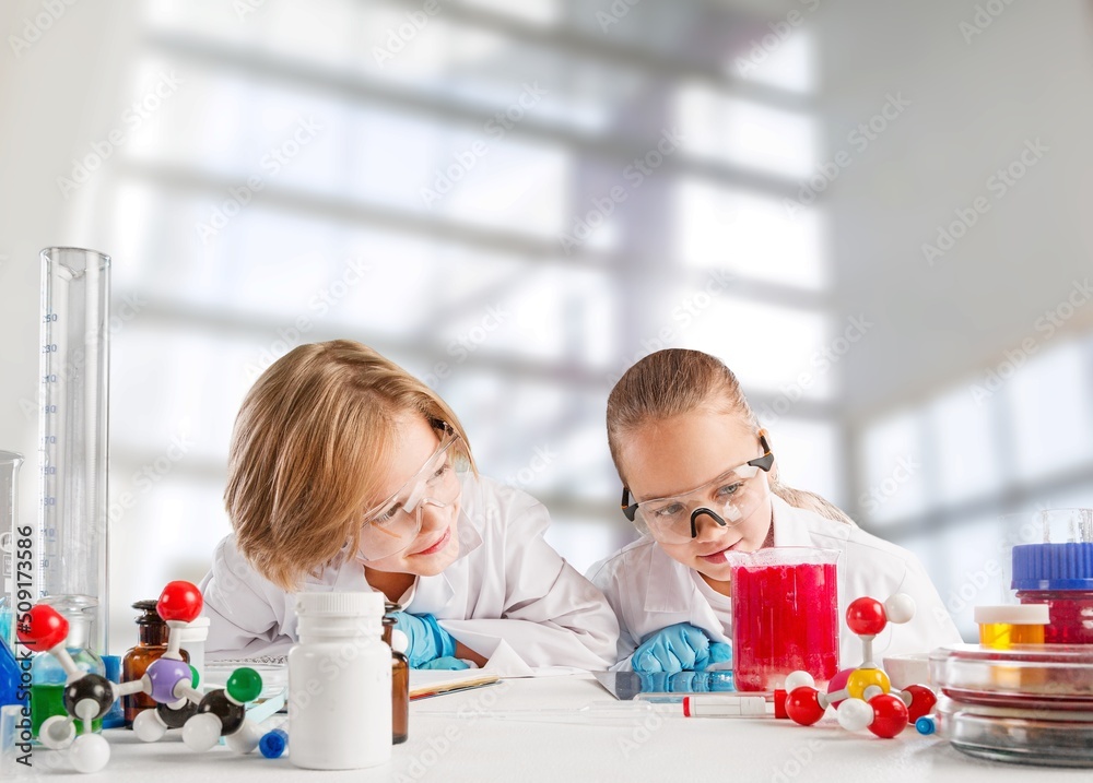 科学化学实验中的聪明男孩戴着防护眼镜，拿着装有liq的瓶子