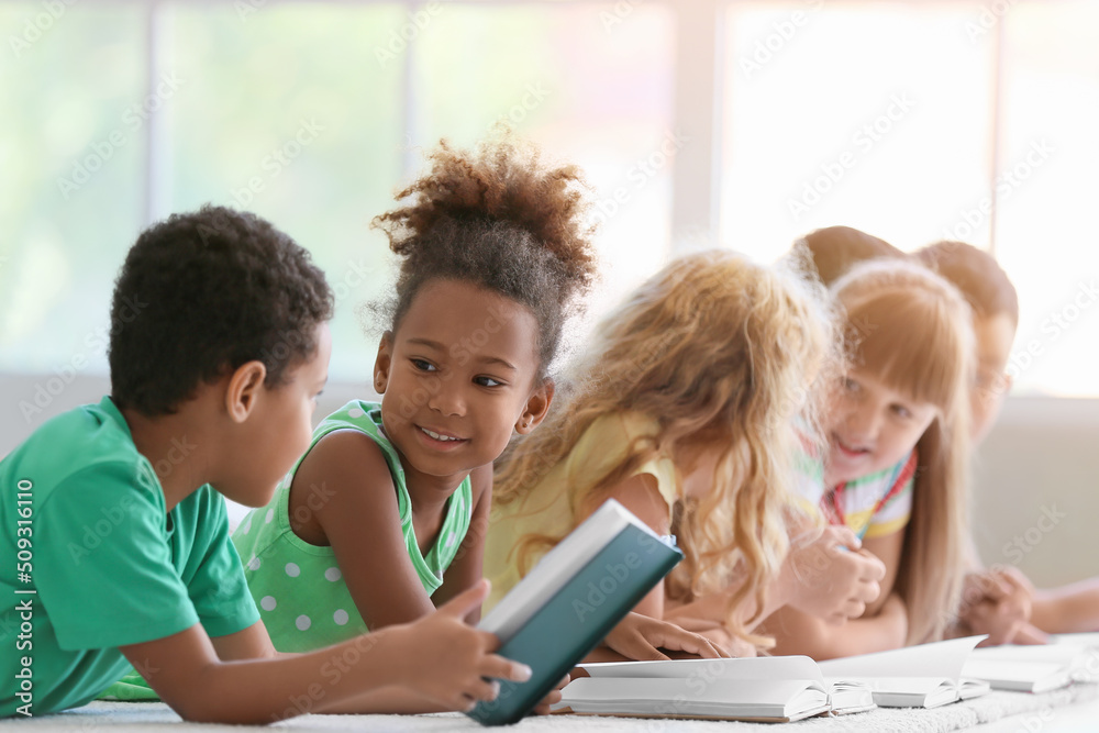 可爱的小孩在教室的地板上看书