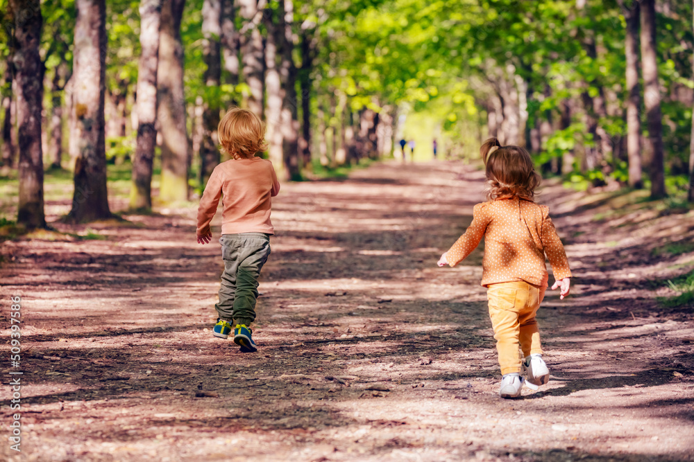 男孩和一个女孩在公园景观的小巷里从后面跑