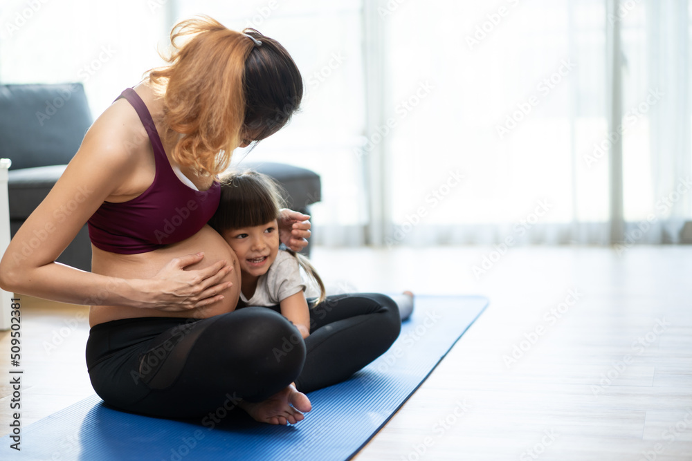 亚洲年轻孕妇和小女孩在家做瑜伽普拉提。