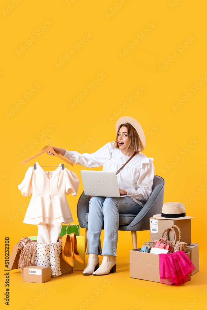 黄底带笔记本电脑和购物袋的年轻女子