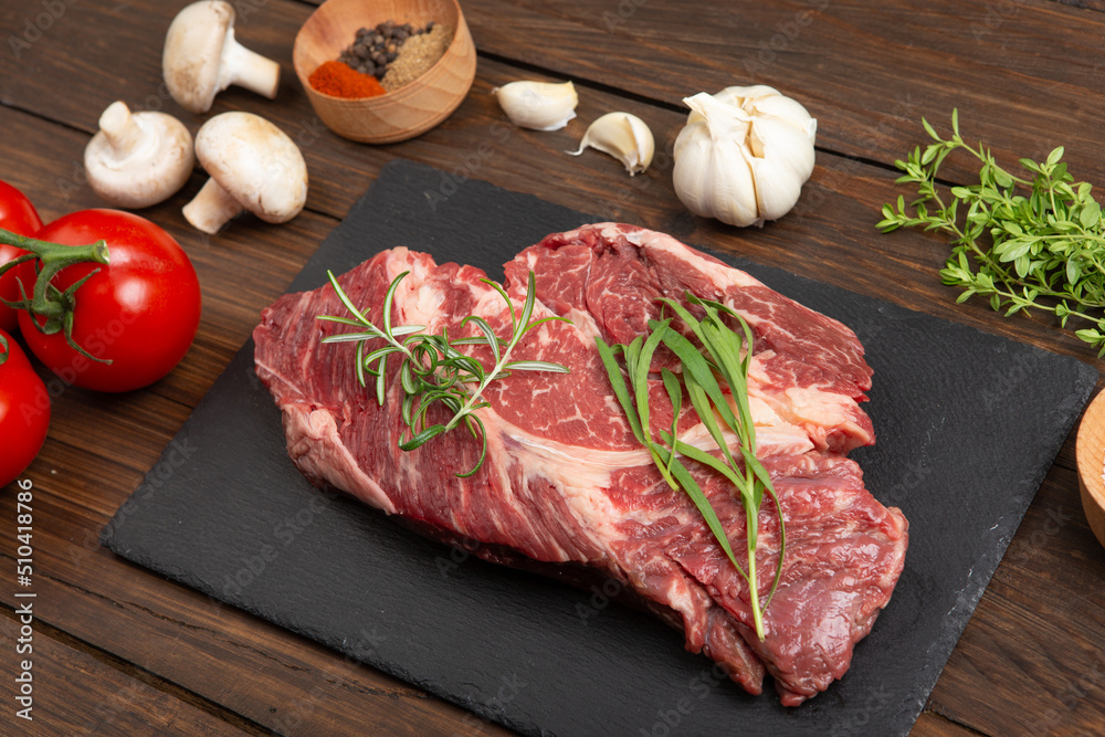 木制桌面上的生牛排。健康食品概念。牛肉片和烹饪烧烤酱的香料