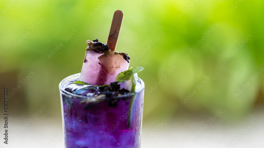 蝴蝶豌豆，蓝豌豆汁冰镇饮料，配酸橙，放在绿色啤酒桶后面的木桌上