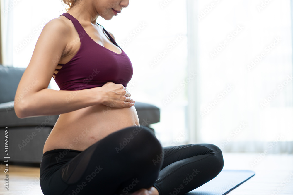 怀孕的亚洲年轻美女在家做瑜伽普拉提锻炼。