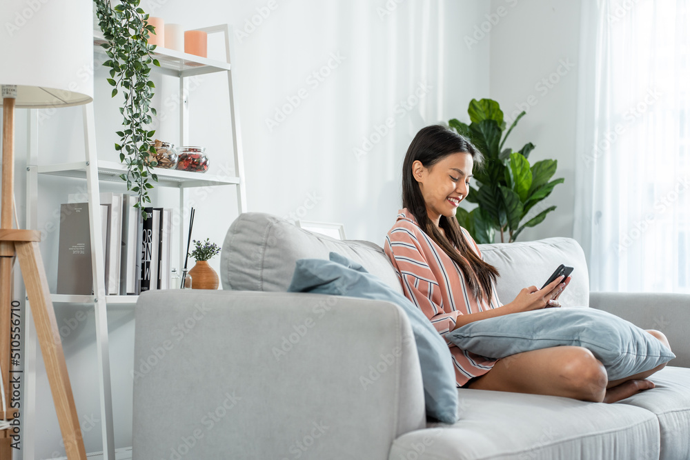 亚洲美女坐在沙发上，在家里刷手机。