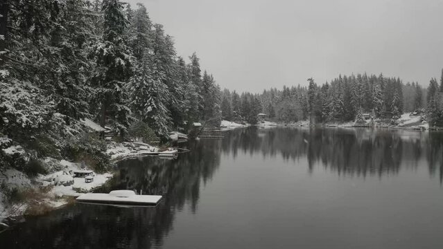 Floating over a lake in winter with the snow falling and calm water.