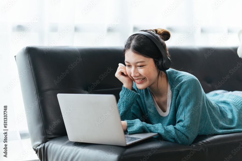 戴着耳机微笑的美丽年轻女子在家通过笔记本电脑视频通话聊天