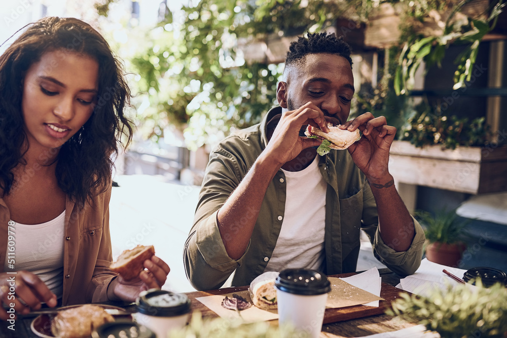 不能拒绝一个好的三明治。一对幸福的年轻夫妇在咖啡馆吃午饭的镜头。