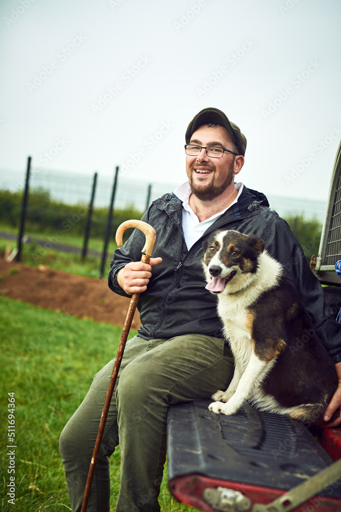 我们一起去任何地方。一个快乐的年轻农民和他的狗在绿地上放松的画像
