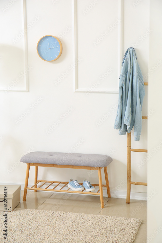 白色墙壁附近舒适的软长凳，配有鞋子和梯子