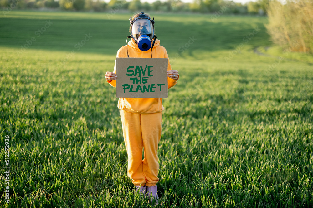 穿着工作服和防毒面具的人站在gre上，手里拿着纸板，上面写着拯救地球的呼吁