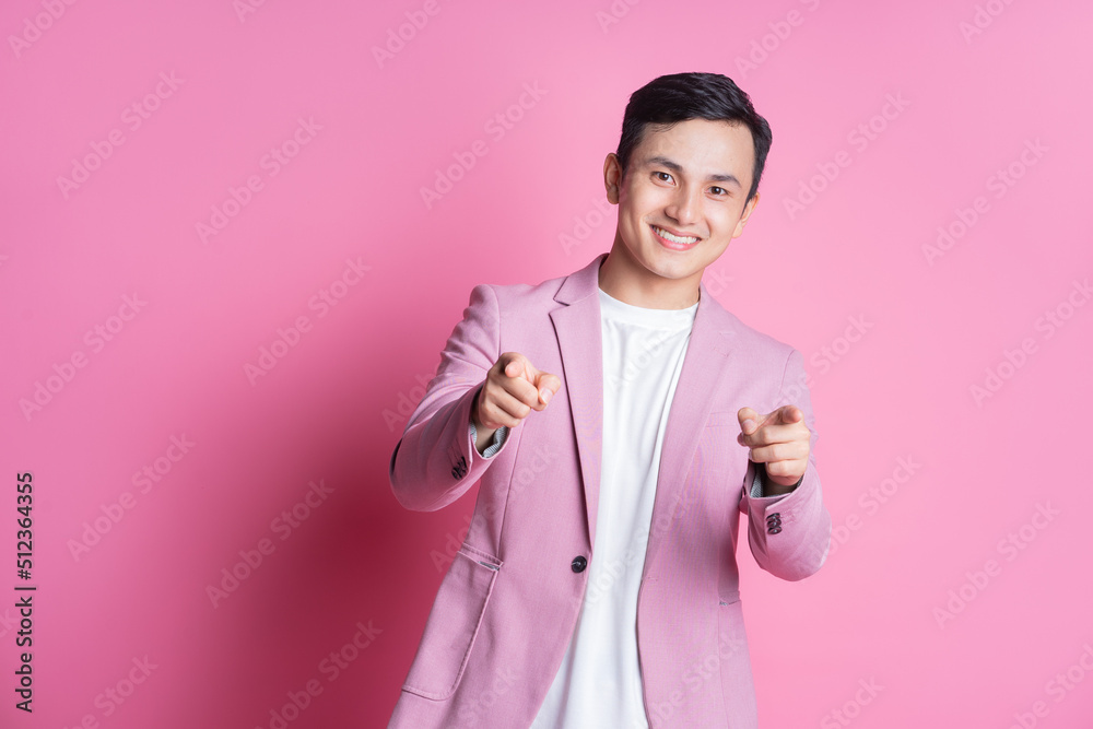 身穿粉色西装的亚洲年轻男子在背景上摆姿势的肖像