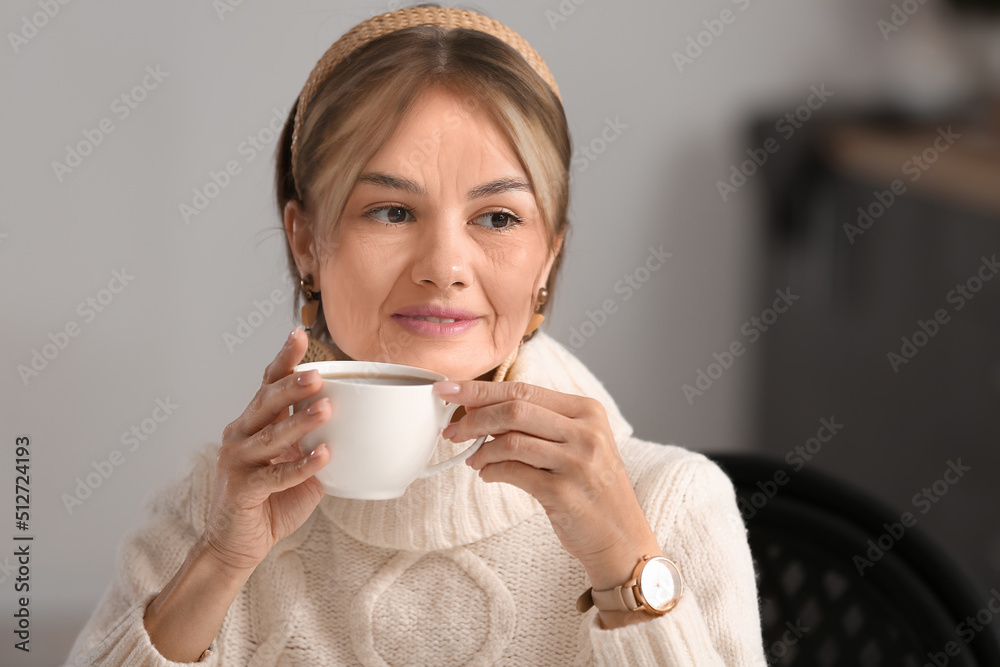 美丽的老年妇女在咖啡馆喝着美味的茶。衰老的过程