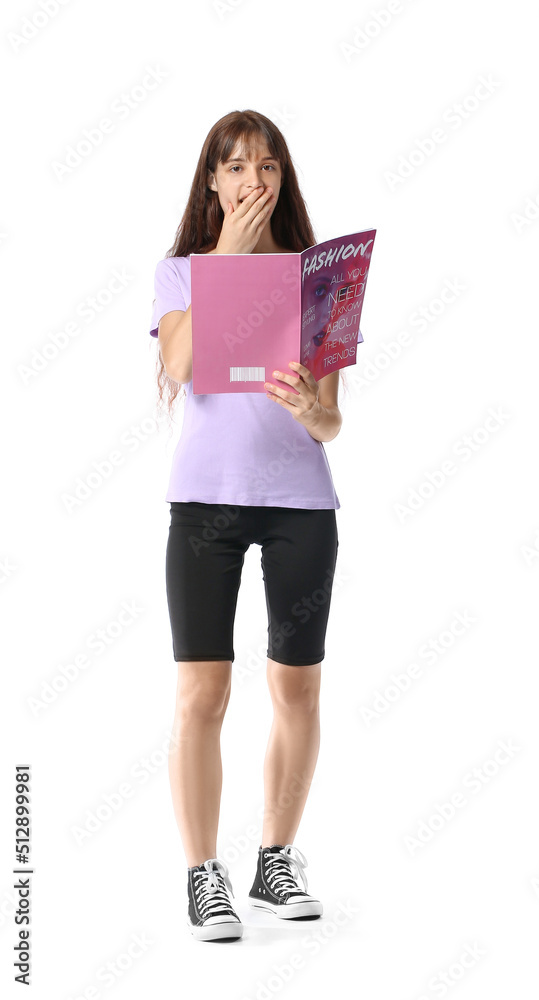 Surprised teenage girl reading magazine on white background