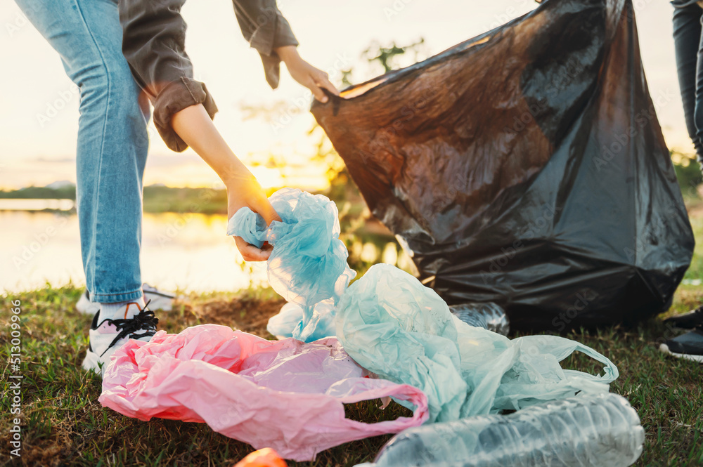 一名妇女在公园里用手捡垃圾塑料进行清洁。