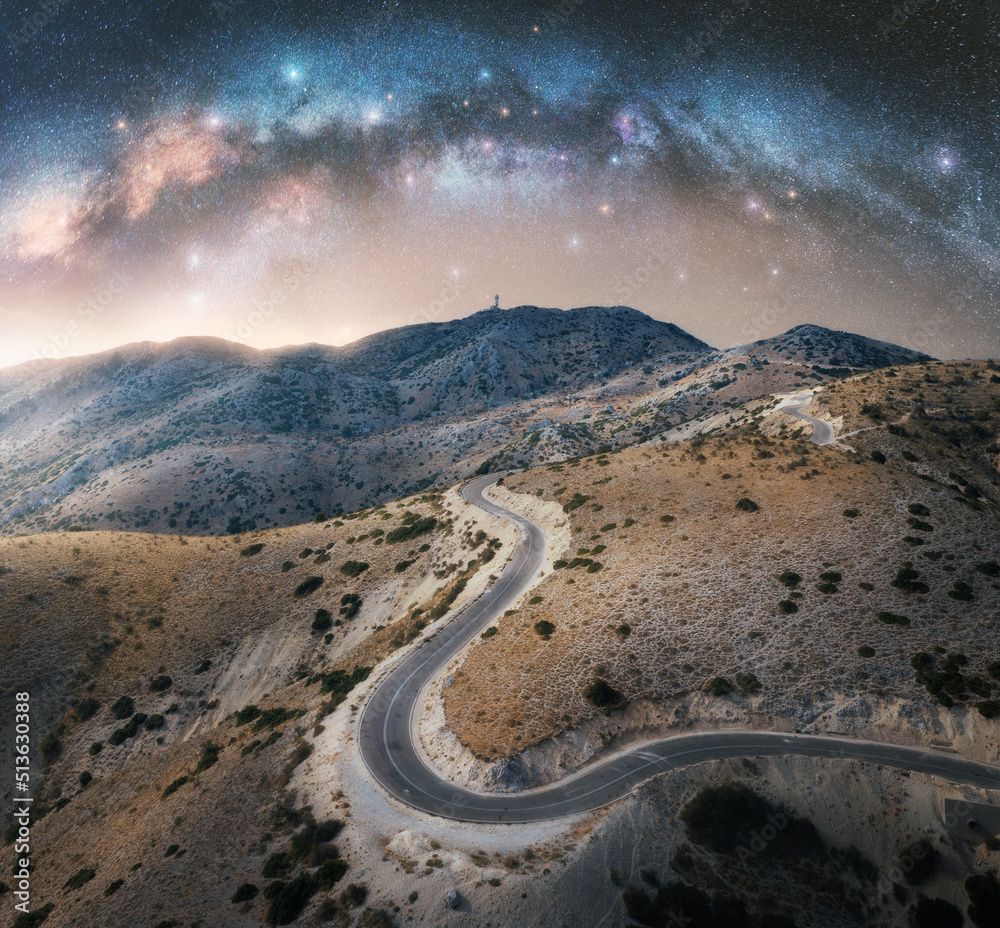 夜晚的银河拱门和蜿蜒的山路。天空中有拱形的银河和明亮的星星
