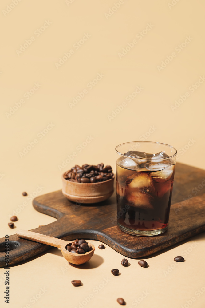 Wooden board with glass of cold brew and coffee beans on color background