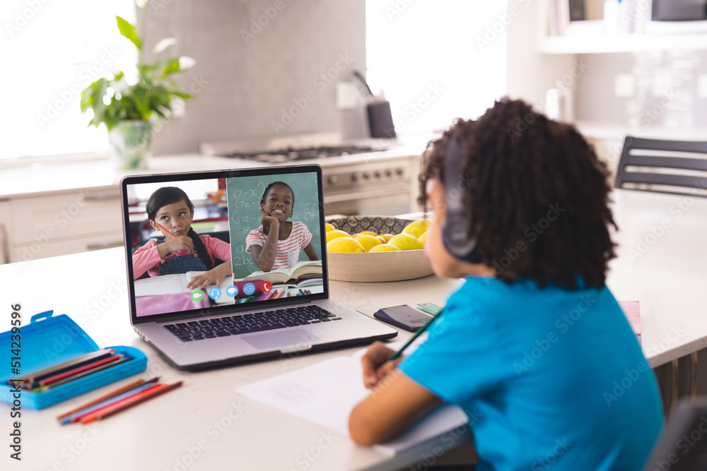 非裔美国男孩戴着耳机和女孩一起看笔记本电脑屏幕在线讲座