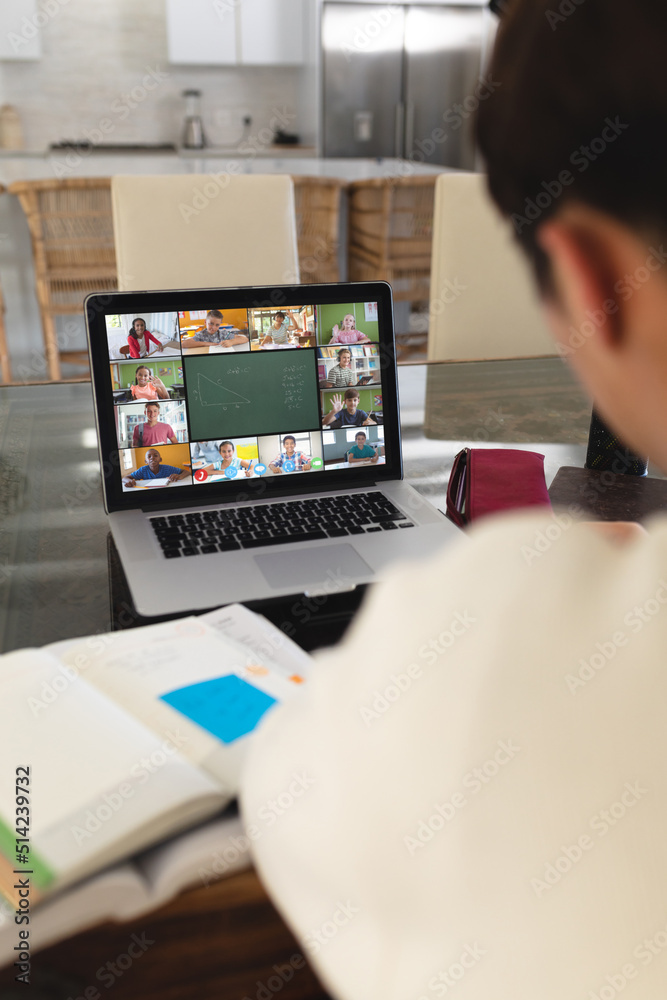 桌上有书的亚洲男孩在家通过笔记本电脑视频通话参加在线讲座