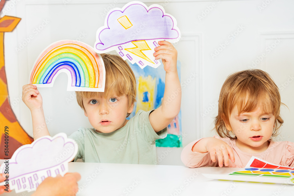 幼儿园男孩展示暴风雨和彩虹天气卡